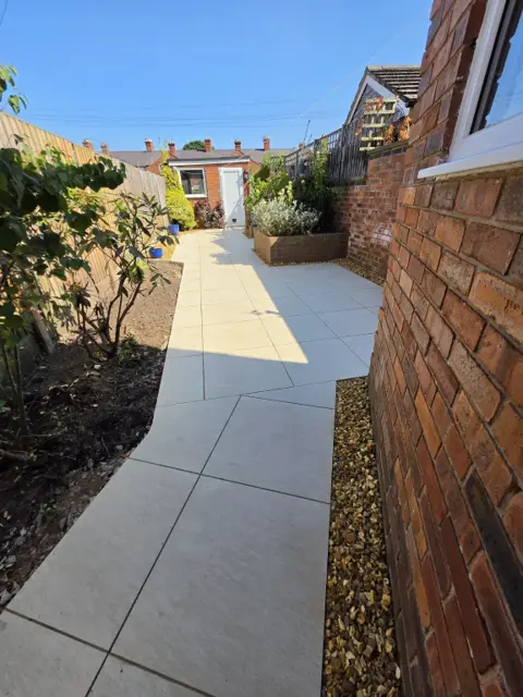 The same rear garden with a new porcelain path and patio leading to the outbuilding