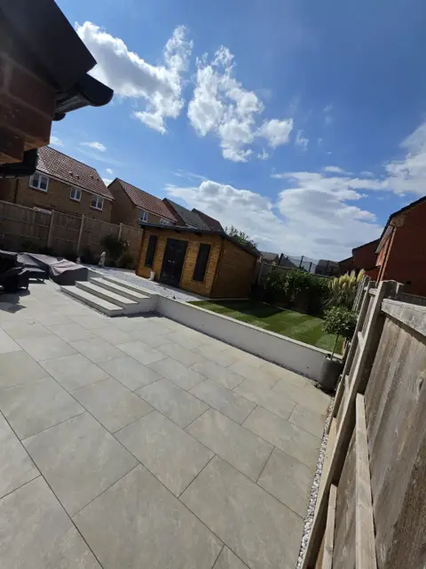 The same garden finished with a porcelain patio, rendered retaining wall, new lawn and garden room
