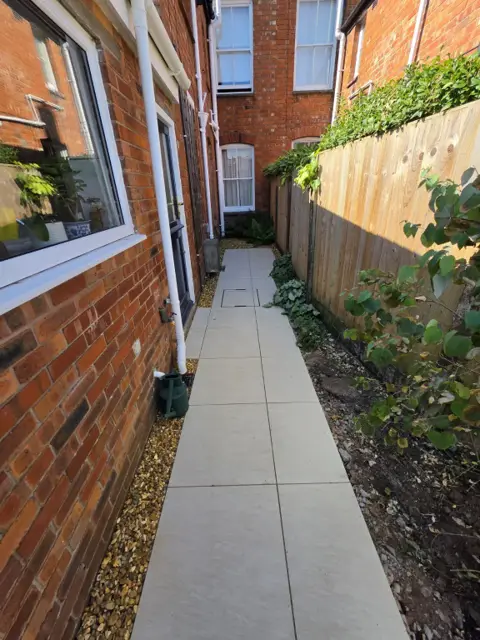 The same side passage relaid with light porcelain paving and gravel edging