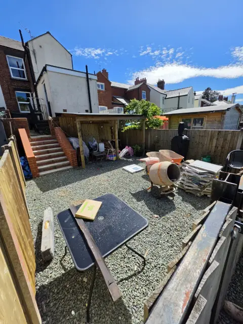 Gravel rear garden cluttered with building materials before the transformation
