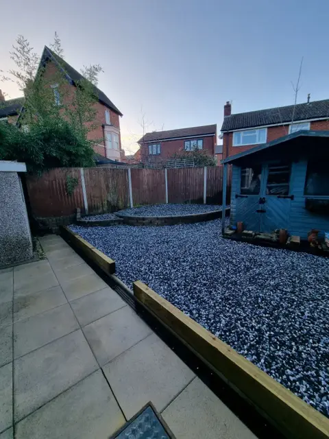 The same rear garden finished with decorative stone and timber sleeper edging