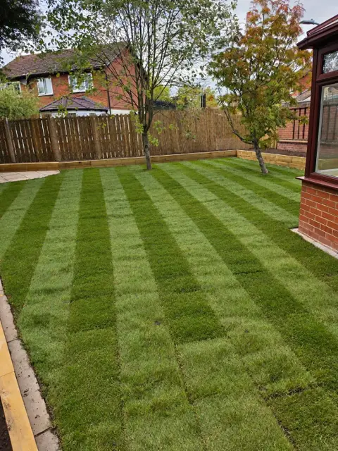 The same rear garden with a new striped lawn and timber sleeper edging